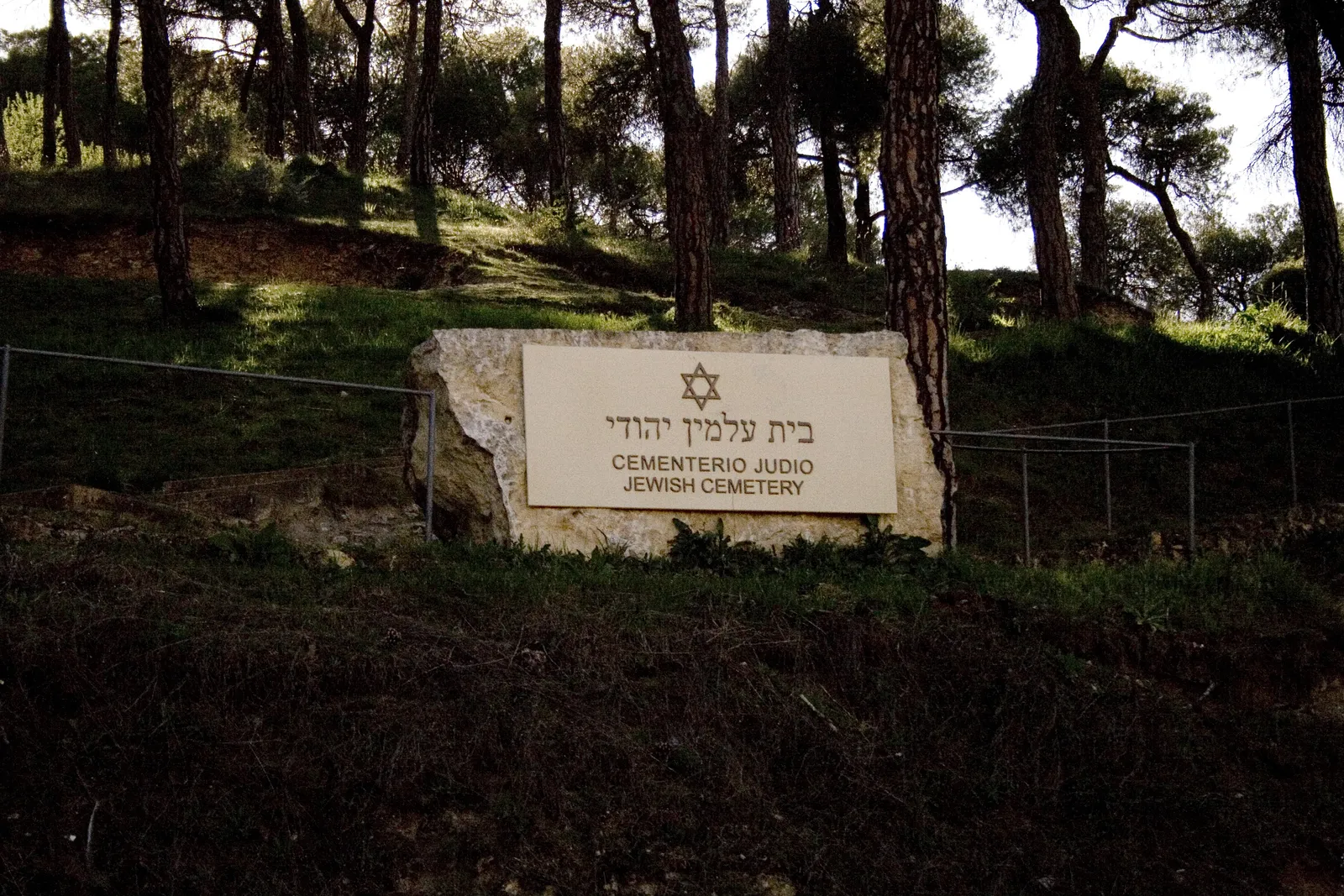 בית הקברות היהודי העתיק של סגוביה, השלט בעברית ובספרדית בין העצים